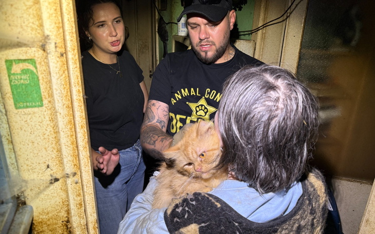 Osoby pomagają w ratowaniu kota w trudnych warunkach.