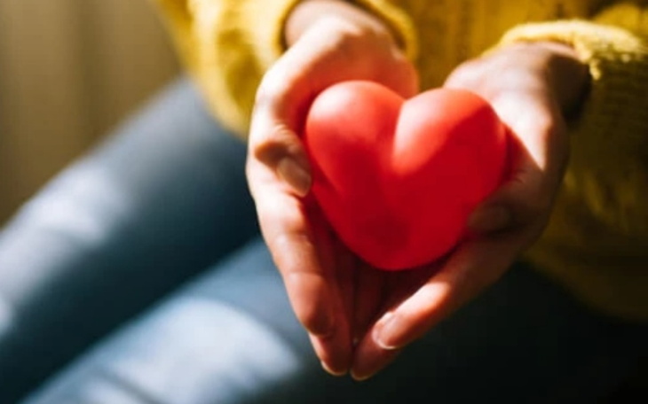 Osoba trzymająca czerwone serce w dłoniach.