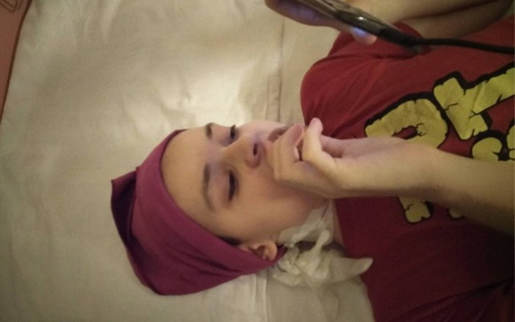 Młody człowiek leżący na łóżku, z telefonem w ręku.