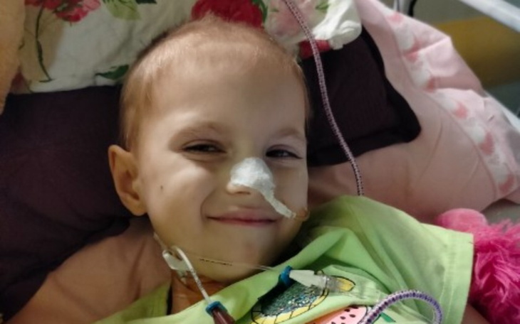 Uśmiechnięte dziecko w szpitalu z rurką nosową.