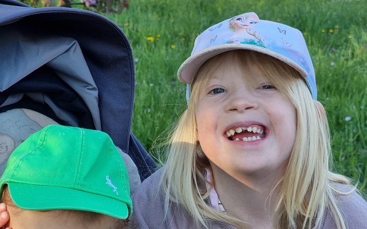 Dziecko z szerokim uśmiechem, w czapce z daszkiem.