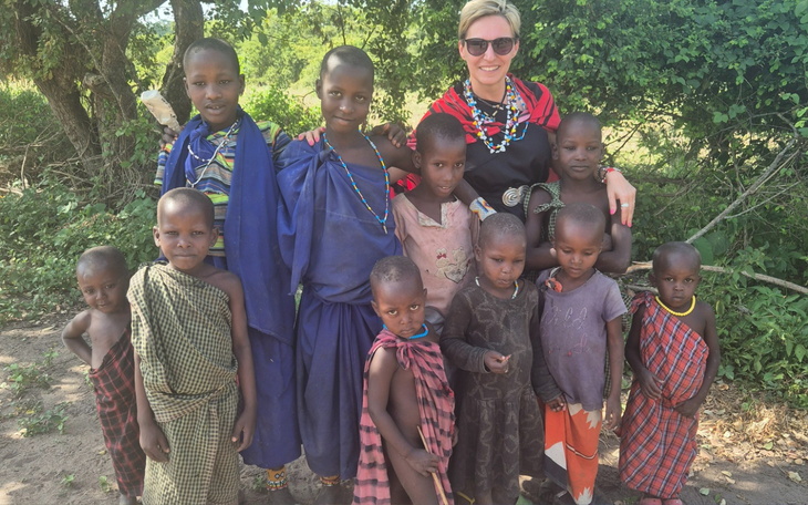 Grupa dzieci w tradycyjnych strojach, pozująca z dorosłą osobą.