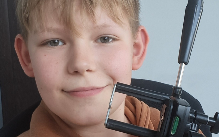 Chłopiec z uśmiechem trzyma sprzęt do nagrywania.