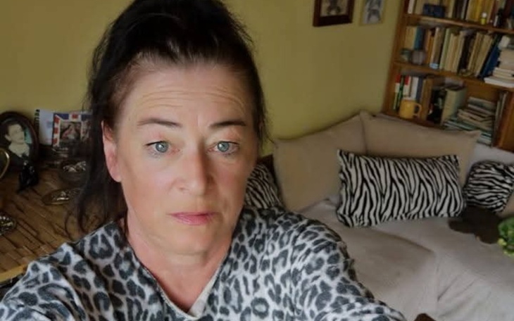 Kobieta w swetrze w panterkę, siedząca w salonie.