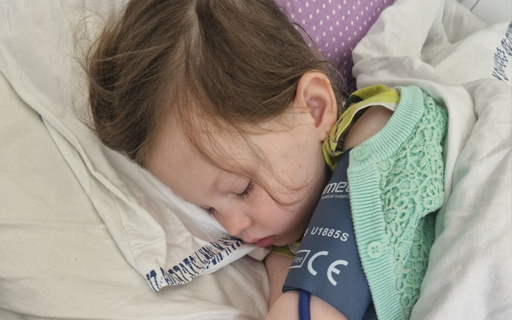 Mała dziewczynka śpiąca w łóżku z ciśnieniomierzem.