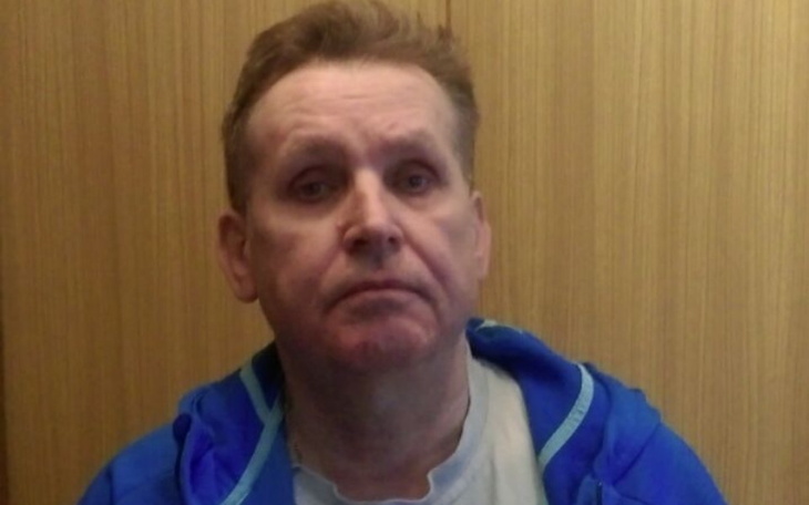 Mężczyzna w niebieskiej kurtce, patrzący w kamerę, z poważnym wyrazem twarzy.