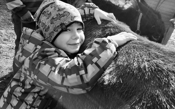 Chłopiec przytulający konia w parku.