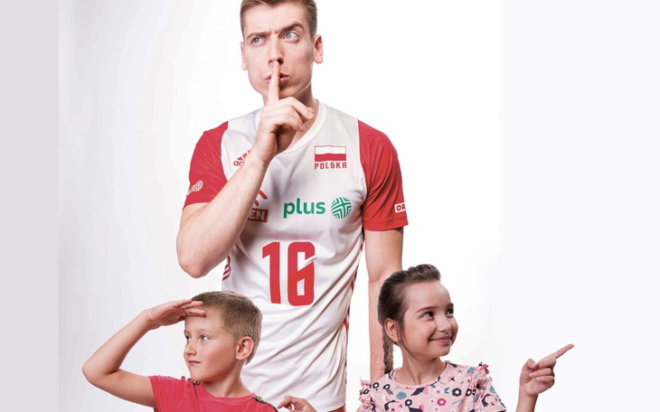 Dzieci z uśmiechem i sportowcem w koszulce reprezentacji Polski.