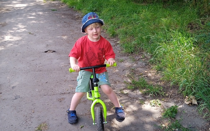 Chłopiec na rowerze bawiący się na leśnej ścieżce.