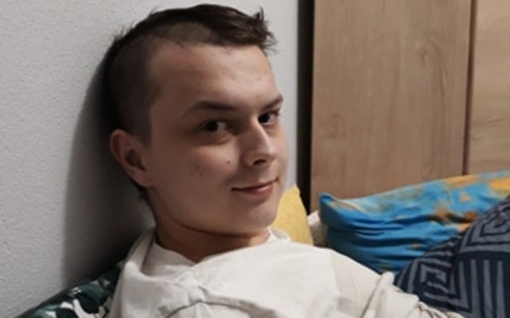 Młody mężczyzna uśmiechający się w szpitalnym łóżku.