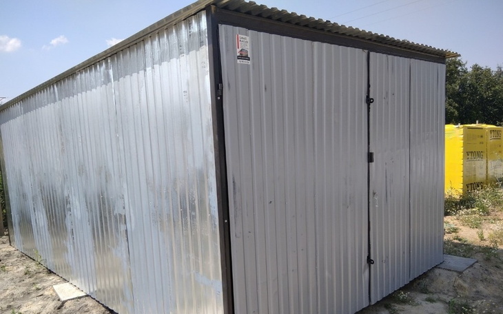 Metalowy kontener na działce, z zamkniętymi drzwiami.