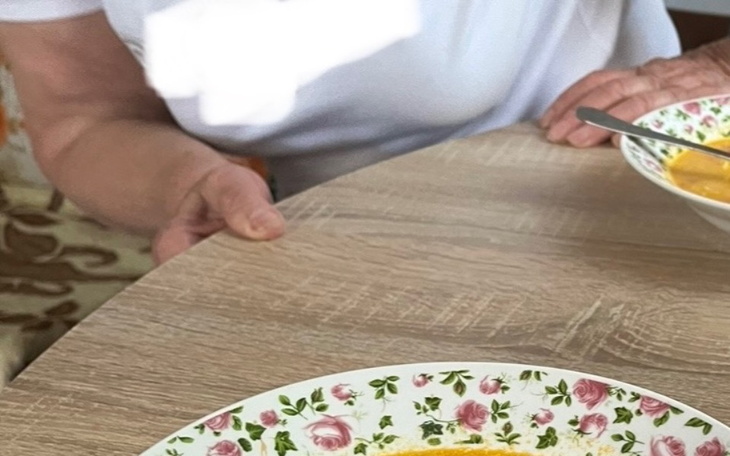 Ręka trzymająca talerz z jedzeniem na stole.