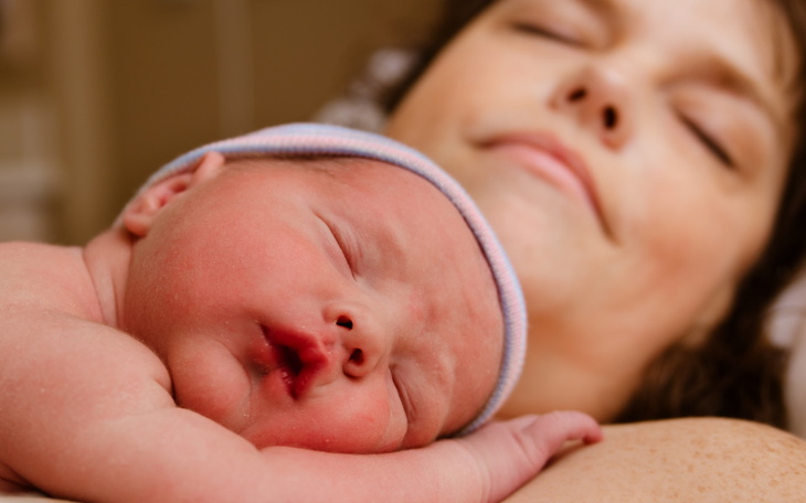 Noworodek śpiący na ramieniu matki, chwila pełna miłości.