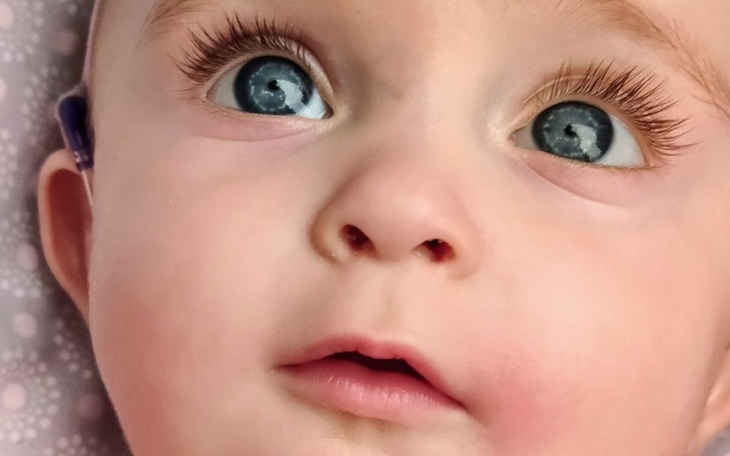 Zbliżenie na twarz niemowlęcia z dużymi, niebieskimi oczami.