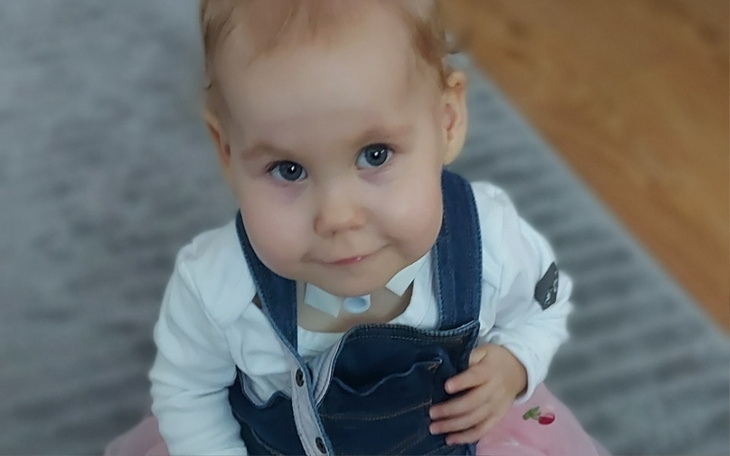 Mała dziewczynka w różowej spódnicy, uśmiechająca się do kamery.