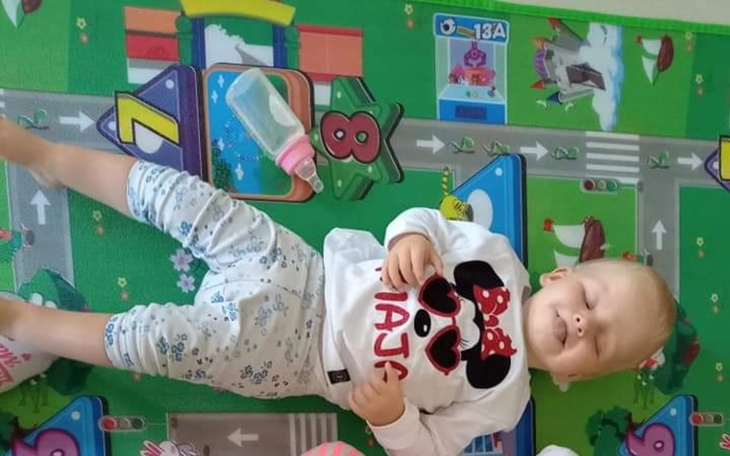 Małe dziecko leżące na macie, uśmiechające się.