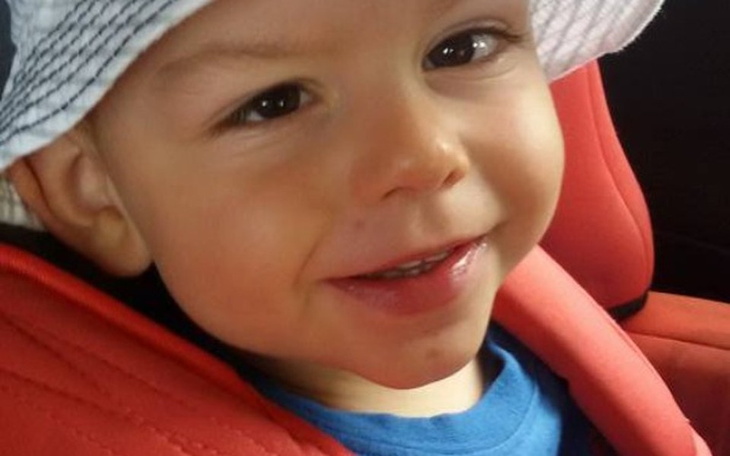 Uśmiechnięty chłopiec w foteliku samochodowym.