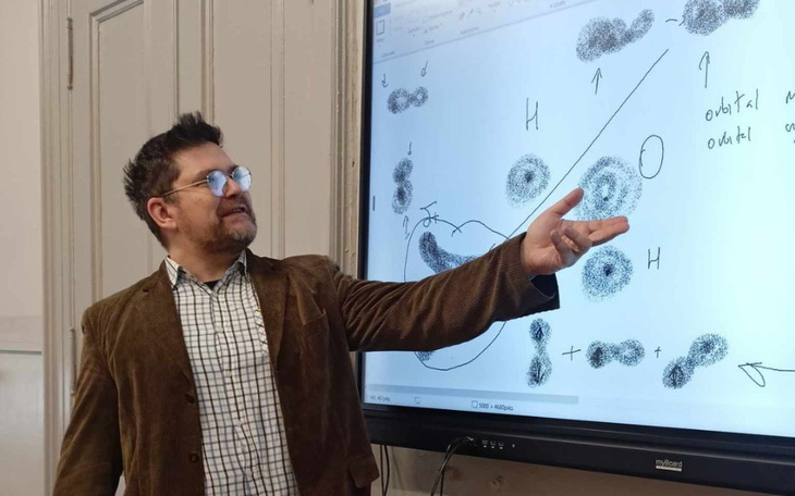 Nauczyciel wskazujący na tablicę z rysunkami.