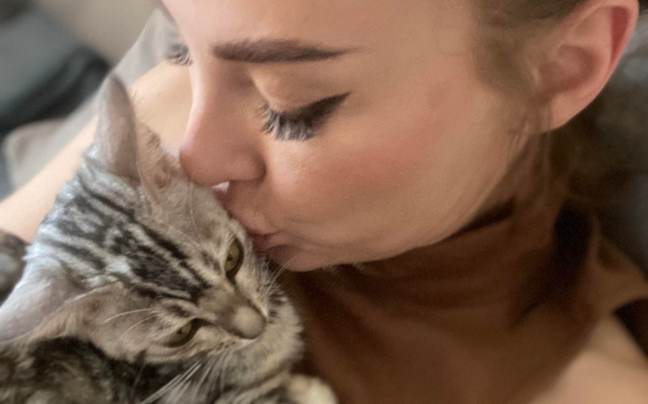 Kobieta całująca kota, chwila bliskości.