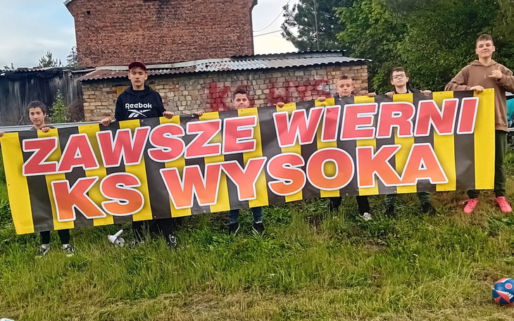 Grupa młodych ludzi trzymających transparent z hasłem wsparcia.