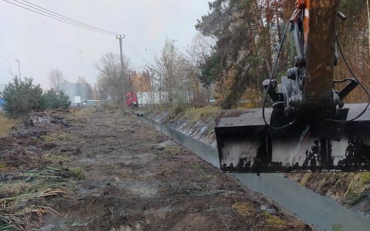 Widok na wykop i maszynę budowlaną przy rowie melioracyjnym.