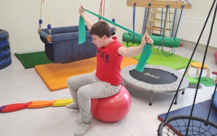Chłopiec ćwiczący w sali rehabilitacyjnej, aktywne wsparcie.