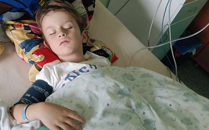 Dziecko śpi w szpitalnym łóżku, spokojny odpoczynek pod kołdrą.