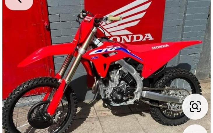 Czerwony motocykl terenowy marki Honda na tle ściany.