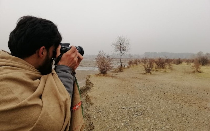 Osoba fotografująca krajobraz w deszczowy dzień.