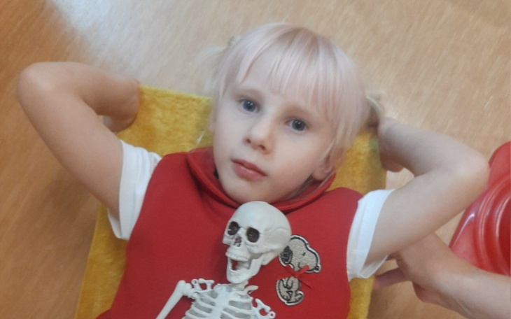 Dziecko leży na podłodze z małym szkieletem obok.