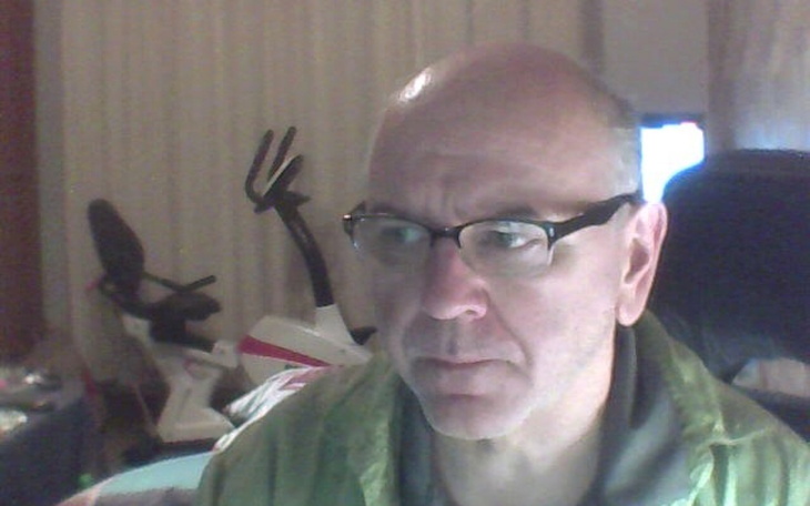 Mężczyzna w okularach, siedzący przy biurku.