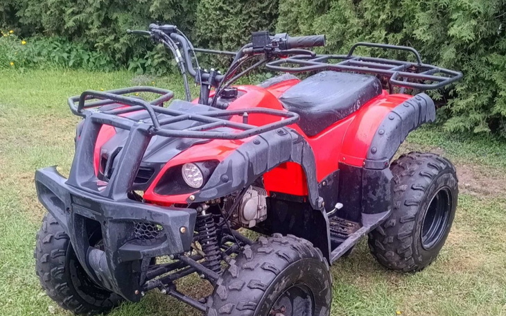 Czerwony quad na tle zielonej trawy.