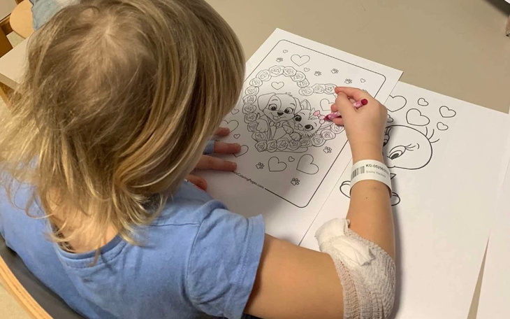Dziewczynka kolorująca obrazek z sercami.