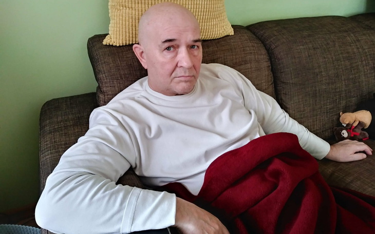 Mężczyzna odpoczywający na kanapie z kocem.