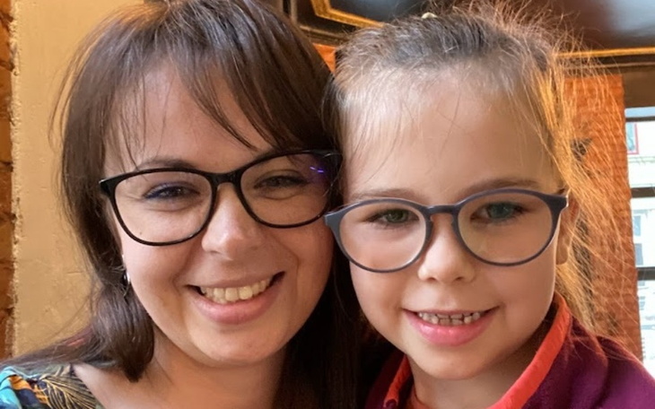 Kobieta i dziewczynka uśmiechają się do aparatu, obie w okularach.