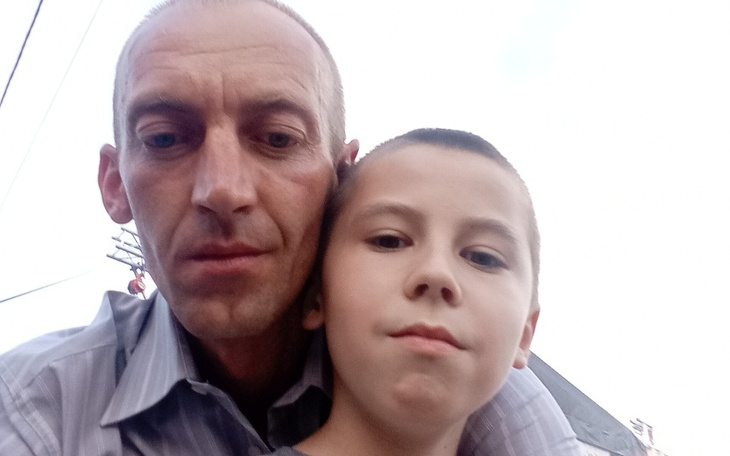 Mężczyzna z chłopcem, obaj uśmiechnięci, pozują do zdjęcia.