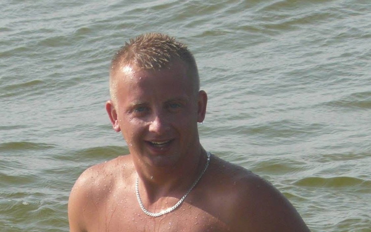 Mężczyzna w wodzie, uśmiechający się do kamery.