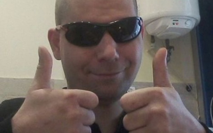 Mężczyzna w okularach przeciwsłonecznych, pokazujący kciuki w górę.