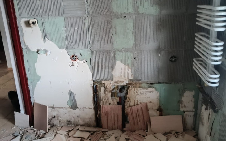 Zniszczona ściana w pomieszczeniu, widoczne odpadające płytki.