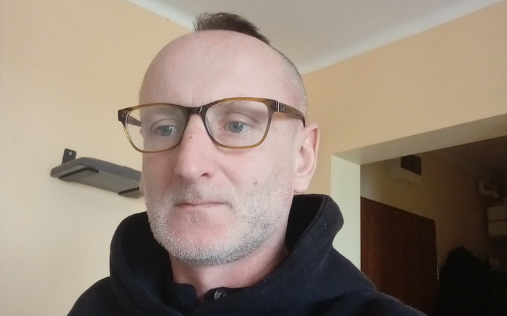 Mężczyzna w okularach, patrzący w kamerę.