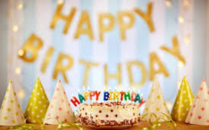 Tort urodzinowy z napisem 'Happy Birthday' i kolorowymi czapkami.