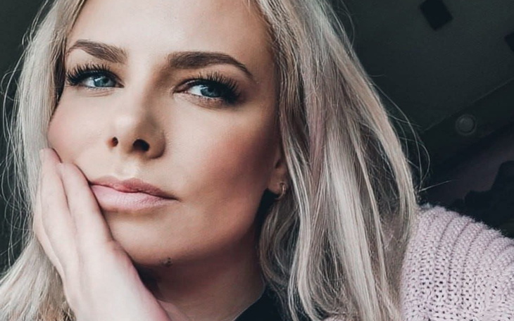 Portret kobiety z wyrazistym makijażem i delikatnym uśmiechem.