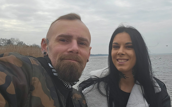 Para na tle jeziora, uśmiechnięta i zrelaksowana.