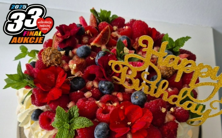 Tort urodzinowy z dekoracjami i owocami.