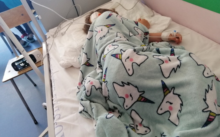 Dziecko śpiące w szpitalu, przykryte kocem.