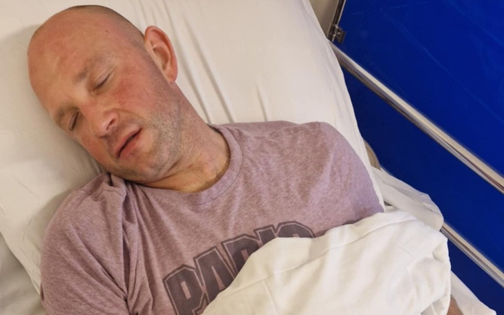 Mężczyzna śpiący na szpitalnym łóżku, wygląda na zmęczonego.