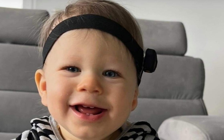 Mały chłopiec z uśmiechem, w czarno-białym stroju.