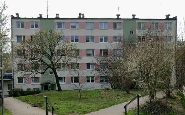 Szkoła lub blok mieszkalny w pastelowych barwach, widok od frontu wiosenna zieleń i alejki.