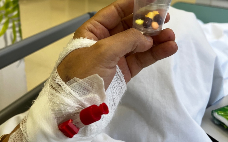 Ręka pacjenta trzymająca leki w szpitalu.