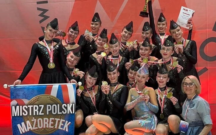 Grupa dziewcząt z medalami na zawodach tanecznych.